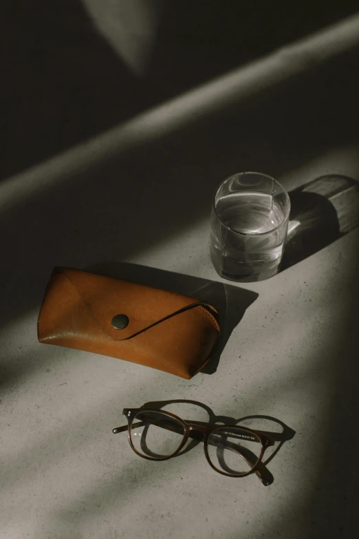 a pair of glasses sitting on top of a table, a picture, leather pouch, archviz, japanese collection product, mid shot photo