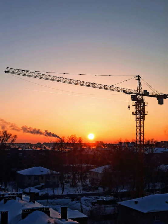 a crane is silhouetted against the setting sun, by Veikko Törmänen, constructivism, 2 0 2 2 photo, winter setting, panorama, bright construction materials