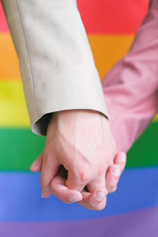 a close up of two people holding hands, an album cover, shutterstock, gay rights, color photograph, ( colorful ), enhanced quality