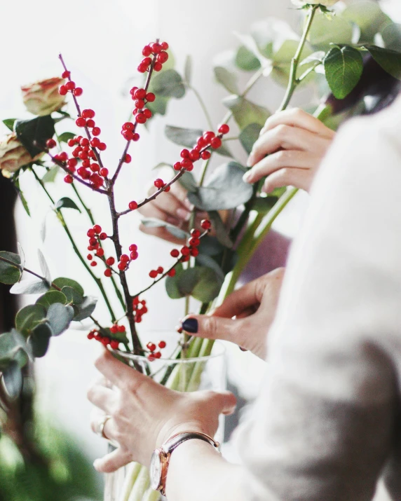 a close up of a person holding a vase of flowers, berries, branches wrapped, multiple stories, eucalyptus