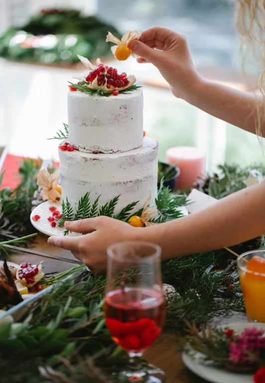 a woman decorating a wedding cake on a table, pexels contest winner, winter setting, fruit, manuka, holiday