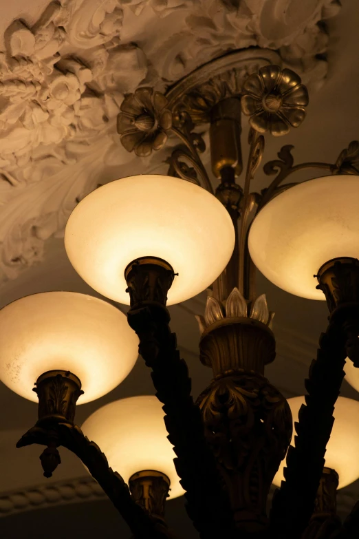 a black and white photo of a chandelier, by Emanuel Witz, trending on unsplash, art nouveau, warm light, blue lamps on the ceiling, ornate with gold trimmings, soft evening lighting