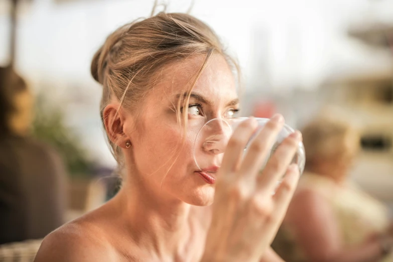 a woman sitting at a table drinking from a glass, pexels contest winner, her face flushing and sweat, blonde swedish woman, mid 2 0's female, hydration