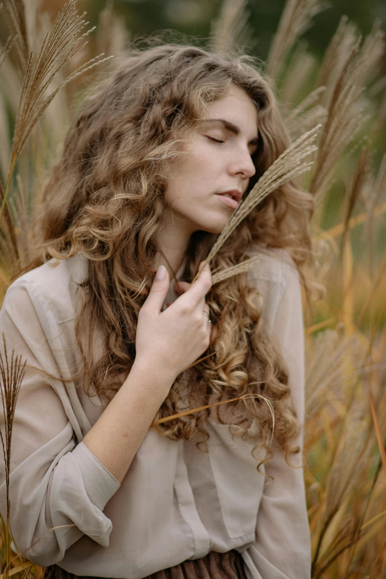 a woman standing in a field of tall grass, by Zofia Stryjenska, trending on pexels, renaissance, curls hair, beige and gold tones, autum, gently caressing earth