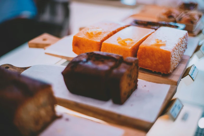 a table topped with lots of different types of pastries, by Lee Loughridge, trending on unsplash, brown bread with sliced salo, orange and black tones, square, in a row