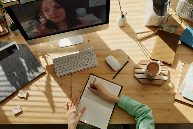 a woman sitting at a desk in front of a computer, a computer rendering, trending on pexels, photograph from above, whiteboards, webcam, brown