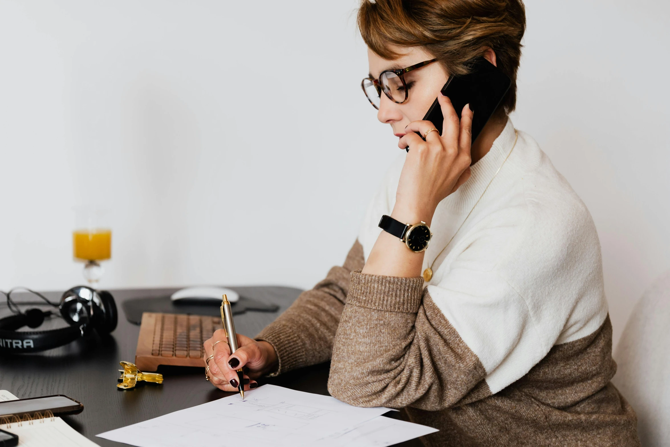 a woman sitting at a desk talking on a cell phone, trending on pexels, writing on a clipboard, black fine lines on warm brown, worksafe. instagram photo, minimalistic