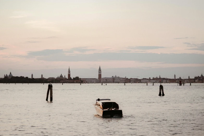 a boat floating on top of a body of water, by Lubin Baugin, pexels contest winner, visual art, venice biennale, late summer evening, soft lilac skies, city in the distance