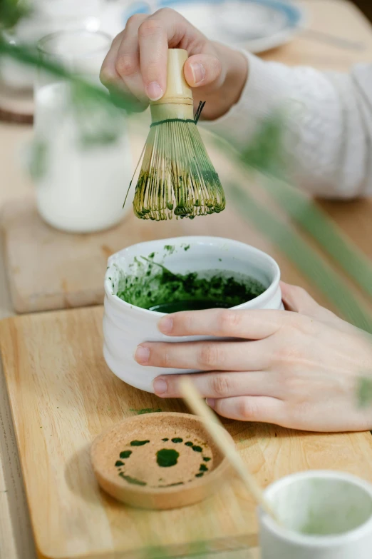 a person holding a whisk over a bowl of green tea, inspired by Kanō Shōsenin, eucalyptus, porcelain organic, powder, promo image