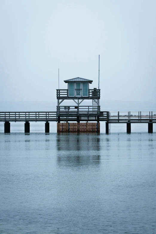 a pier in the middle of a body of water, watch tower, muted cold colors, foggy day outside, dan mumfor