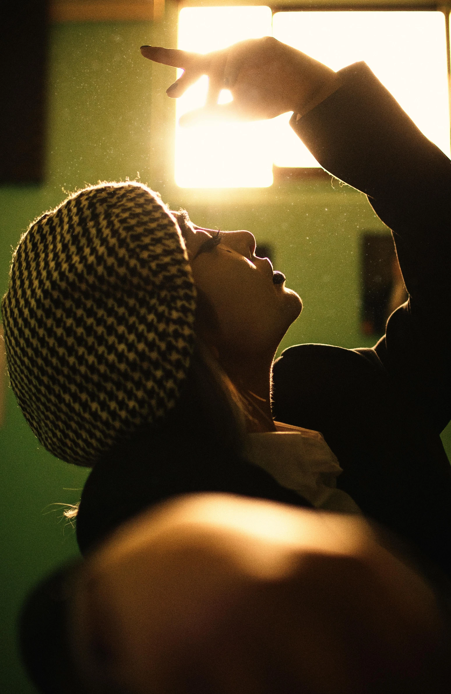 a person holding a cell phone up in the air, by Andrew Domachowski, light and space, beanie, checking her phone, back light, film movie still