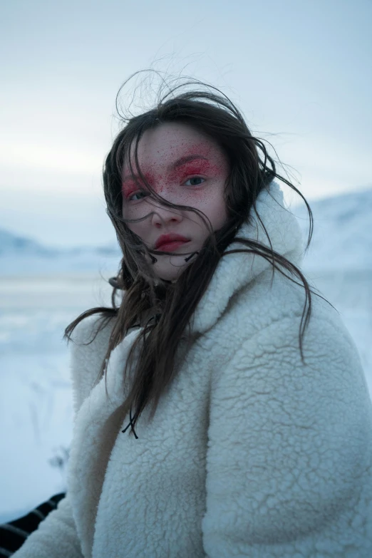 a woman in a white coat standing in the snow, an album cover, inspired by Louisa Matthíasdóttir, pexels contest winner, red contact lenses, inuit, rugged face, movie still 8 k