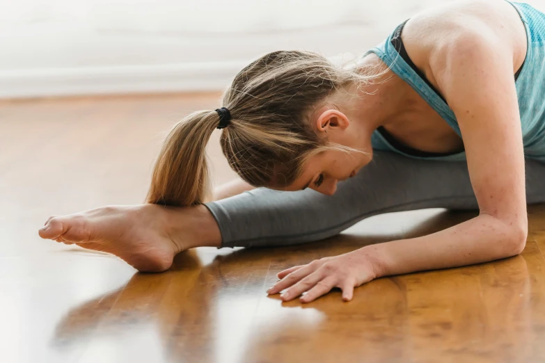 a woman doing a yoga pose on the floor, by Julian Allen, unsplash, arabesque, sydney hanson, profile image, doing splits and stretching, as well as scratches