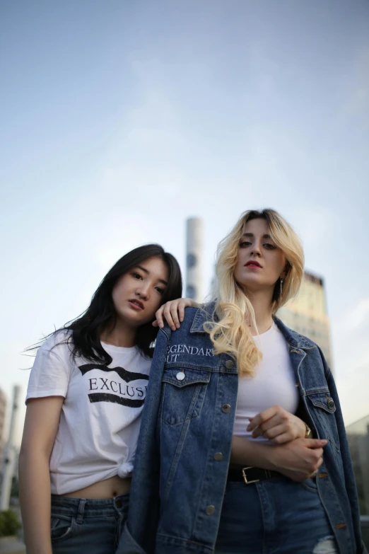a couple of women standing next to each other, trending on pexels, realism, outlive streetwear collection, denim jacket, ava max, skyline