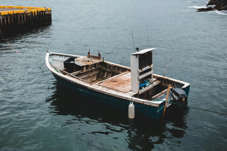 a small boat sitting on top of a body of water, pexels contest winner, under repairs, built around ocean, fishing, manly