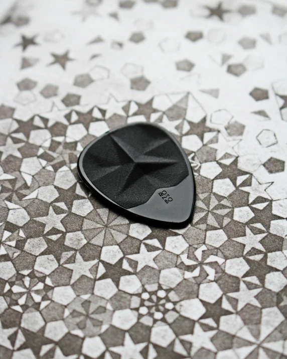 a guitar pick sitting on top of a tiled floor, all black matte product, 9 9 designs, dof, large