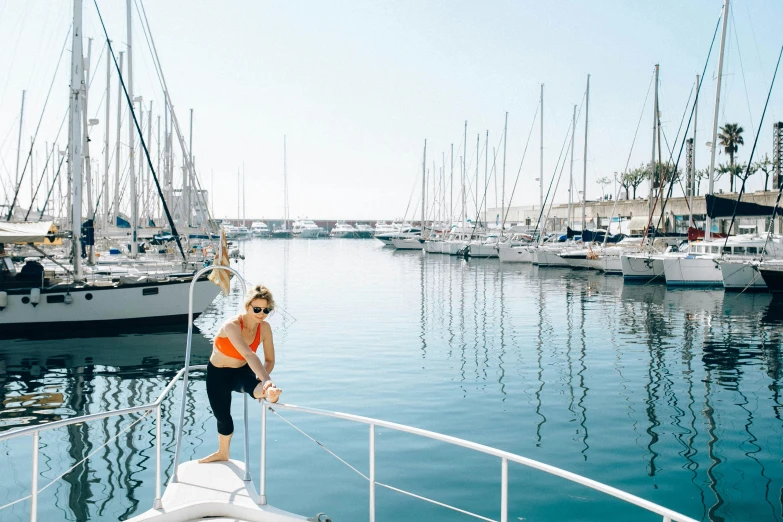 a woman standing on the bow of a boat, a picture, marbella, dingy gym, summer vibe, city docks