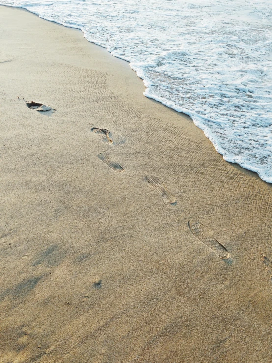 a couple of footprints that are in the sand, an album cover, pexels contest winner, on the ocean water, profile image, 10k, no watermark