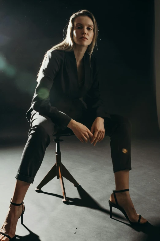 a woman sitting on a chair in a dark room, by Nina Hamnett, trending on pexels, wearing causal black suits, modeling studio, met collection, **cinematic