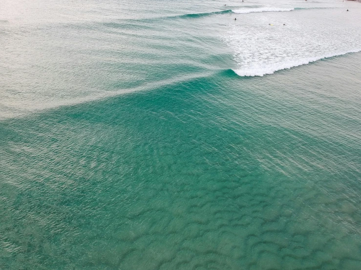 a person riding a surfboard on a wave in the ocean, inspired by Andreas Gursky, unsplash contest winner, minimalism, the emerald coast, seen from a plane, glistening seafoam, australian beach