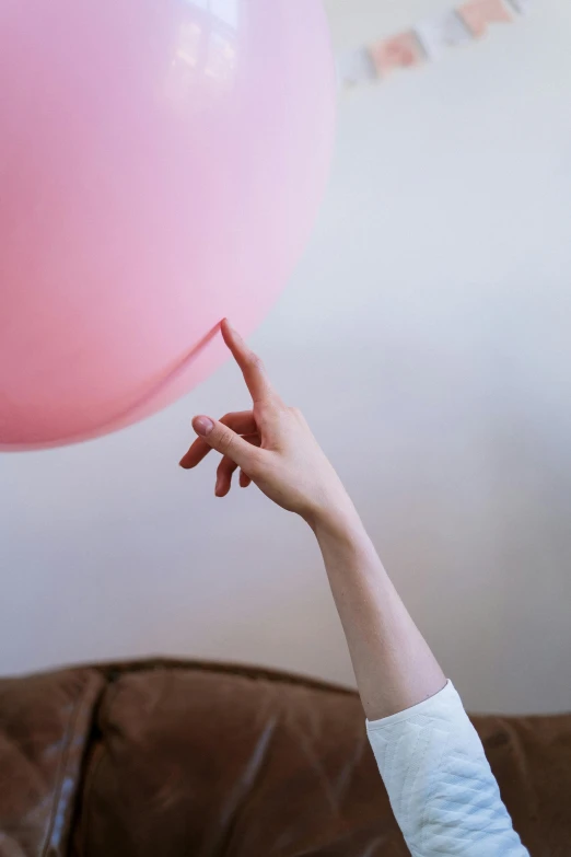 a woman holding a pink balloon above her head, trending on pexels, close-up of thin soft hand, pointing, at home, large)}]