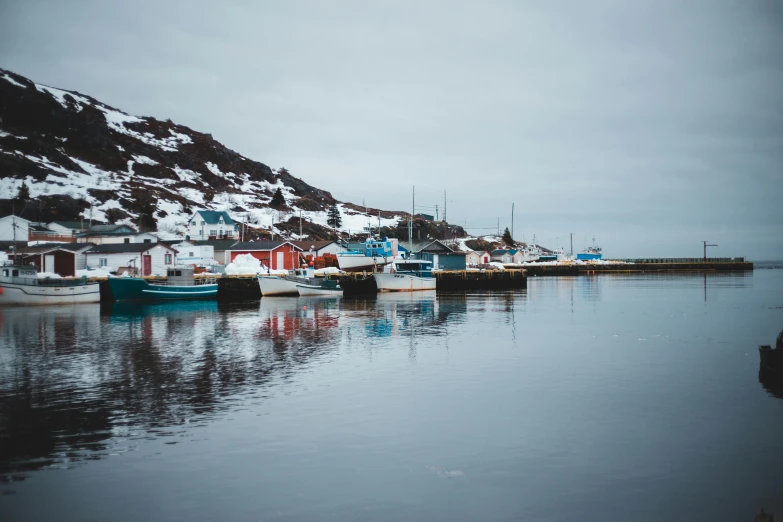 a group of boats sitting on top of a body of water, by Terese Nielsen, pexels contest winner, hurufiyya, cold colours, small port village, winter setting, in a row