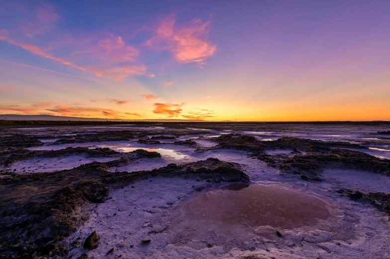 a large body of water sitting on top of a sandy beach, a picture, by Lee Loughridge, unsplash contest winner, purple sunset, rock pools, salt dunes, australian outback