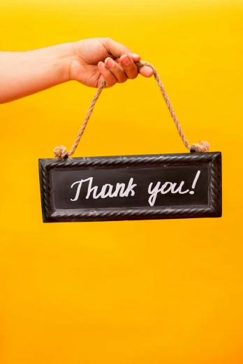 a person holding a sign that says thank you, by Arabella Rankin, trending on unsplash, yellow and black trim, close - up studio photo, slide show, blackboard