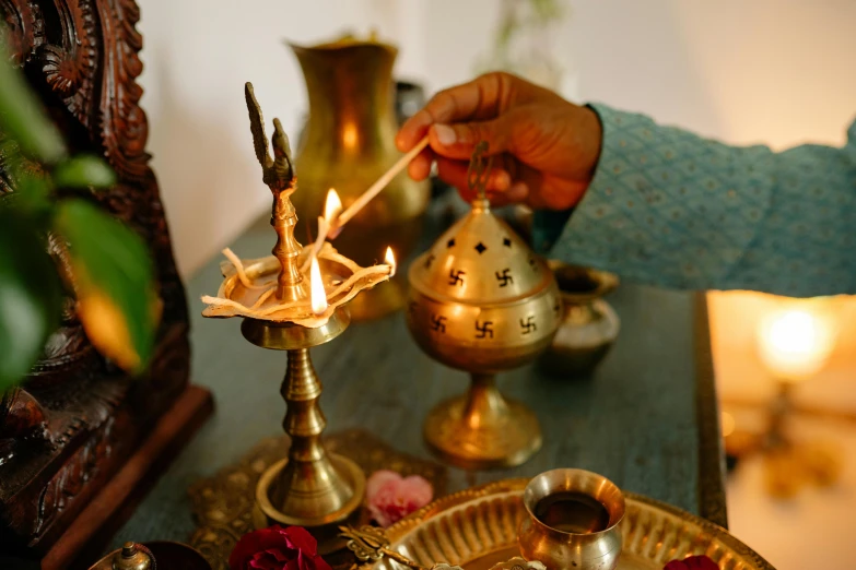 a person lighting a candle on a table, hurufiyya, hindu aesthetic, brass and copper, thumbnail, brown