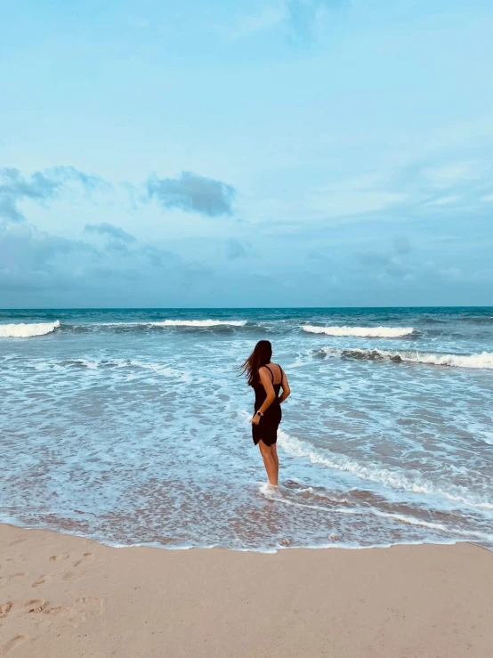 a woman standing on top of a beach next to the ocean, in the water, profile image