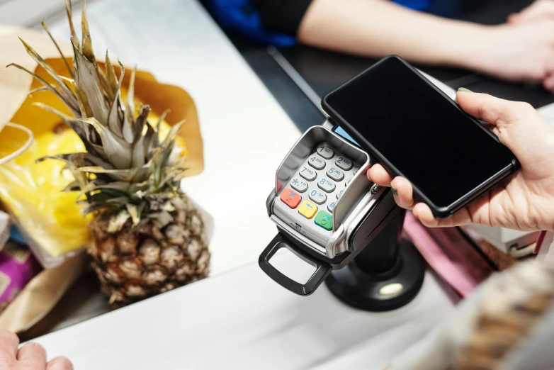 a person holding a cell phone next to a pineapple, cash register, 15081959 21121991 01012000 4k, square, australian