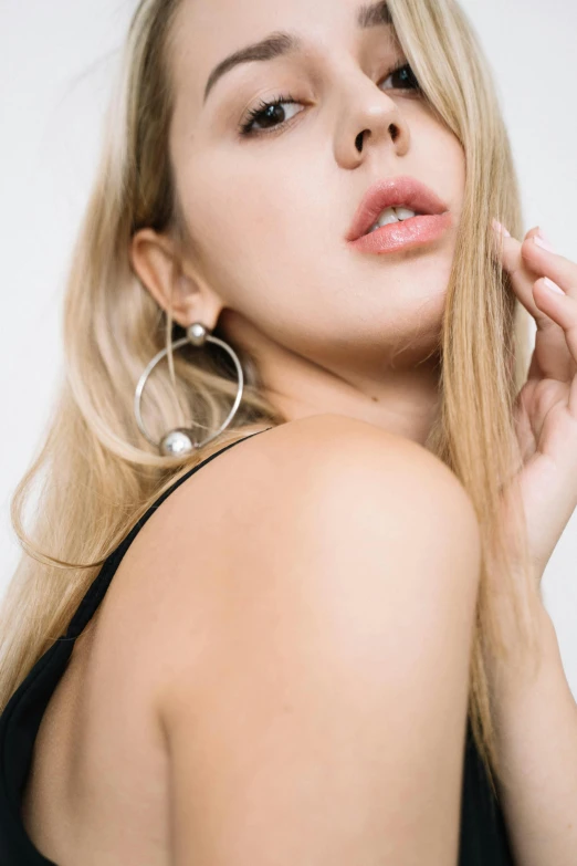 a woman in a black dress posing for a picture, an album cover, by Nina Hamnett, trending on pexels, wearing pearl earrings, big hooped earrings, silver，ivory, model エリサヘス s from acquamodels