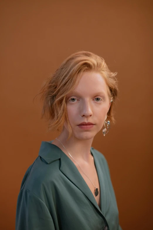 a woman standing in front of a brown background, unsplash, photorealism, hr ginger, young handsome pale roma, hammershøi, on a pale background