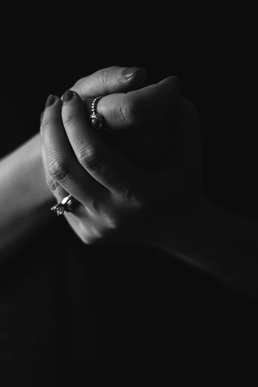 a black and white photo of a woman's hands, unsplash, praying, rings, ominous, woman