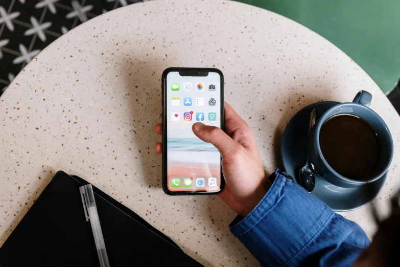 a person holding an iphone next to a cup of coffee, trending on pexels, avatar image, iphone 12, thumbnail, background image