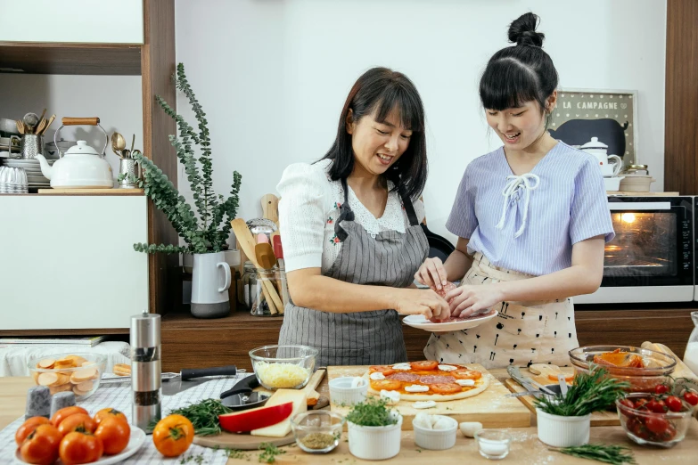 a couple of women standing next to each other in a kitchen, inspired by Yukimasa Ida, pexels contest winner, cooking pizza, avatar image, asian female, hands on counter