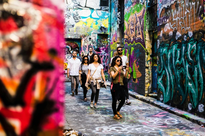 a group of people walking down a street, graffiti, rich colourful, aussie, wanderlust, alley