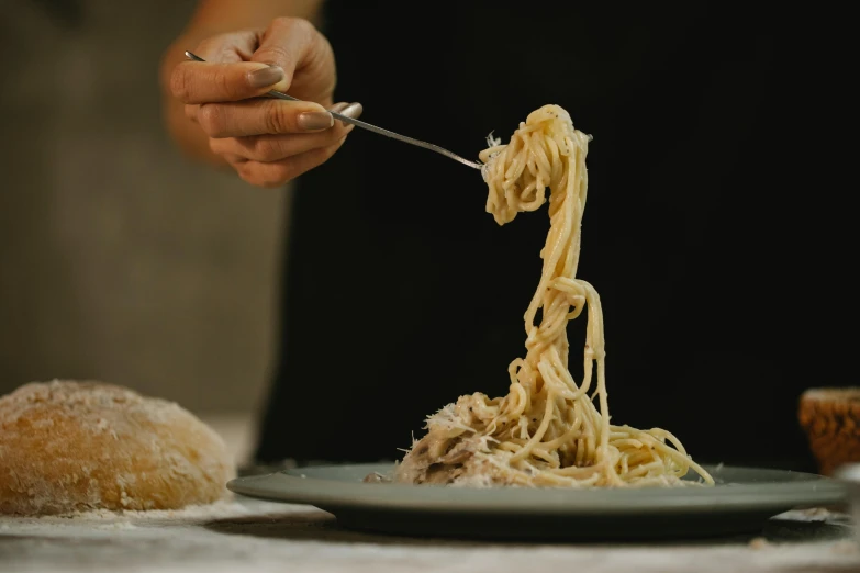 a person holding a fork over a plate of pasta, silver，ivory, blonde crea, pulling strings, mid shot