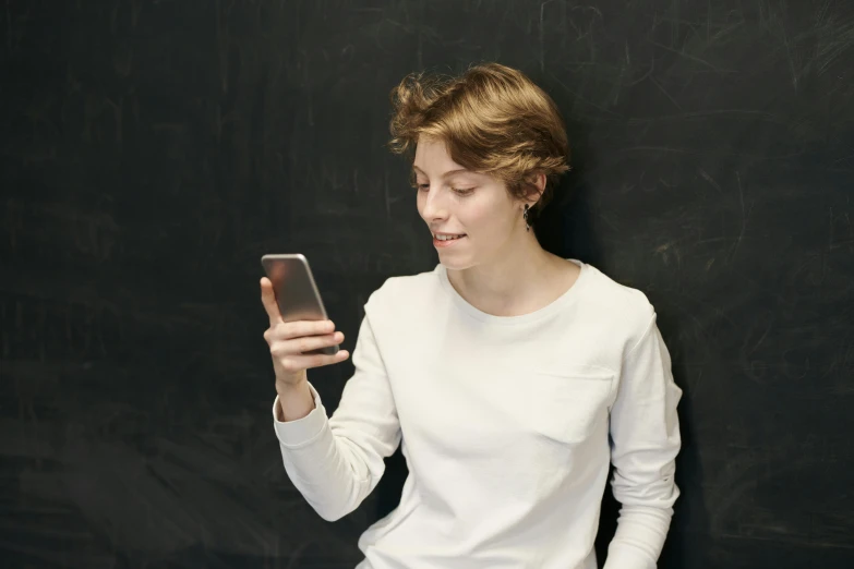 a woman standing in front of a blackboard holding a cell phone, a picture, trending on pexels, renaissance, boy with neutral face, teenage boy, with a white, casually dressed