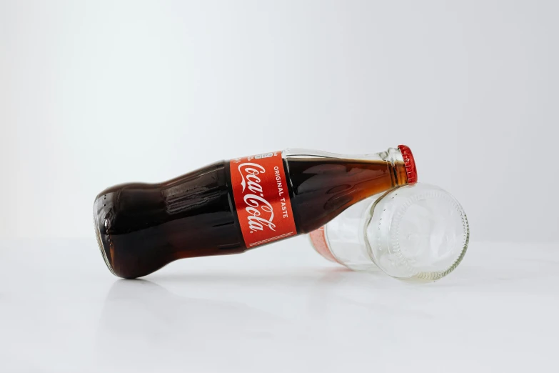 a bottle of coke sitting on top of a table, with clear glass, dezeen, product view, red