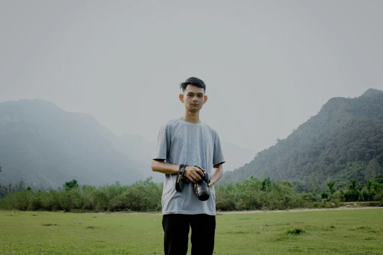a man standing on top of a lush green field, a picture, inspired by Huang Binhong, pexels contest winner, realism, holding a camera, phong shaded, thin young male, avatar image