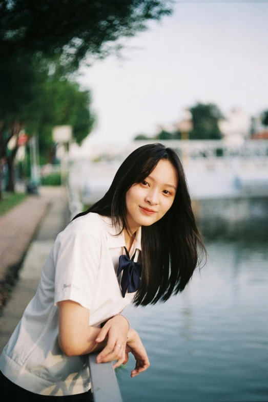 a woman leaning on a railing next to a body of water, by Tan Ting-pho, happening, portrait of high school girl, 8 k ), full frame image, lofi portrait