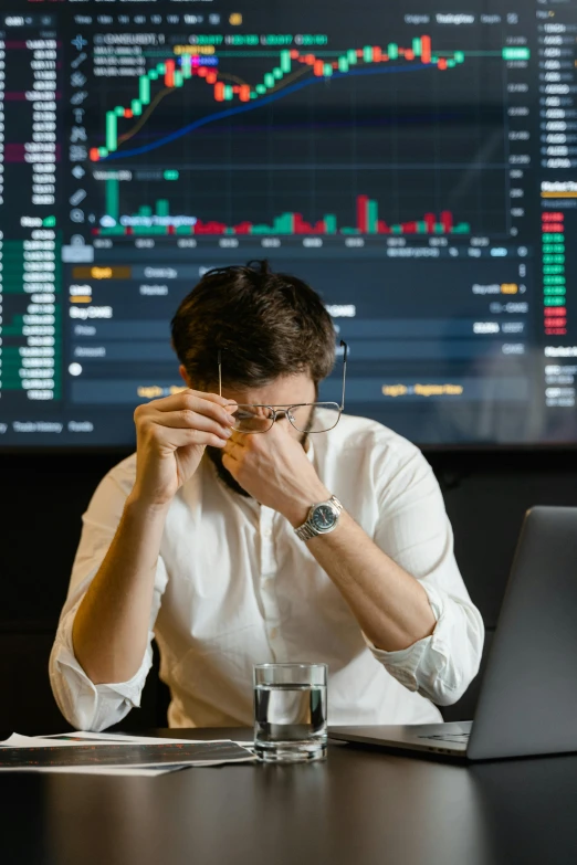 a man sitting at a table with a laptop in front of him, a picture, trending on unsplash, renaissance, displaying stock charts, people crying, mining, crypto