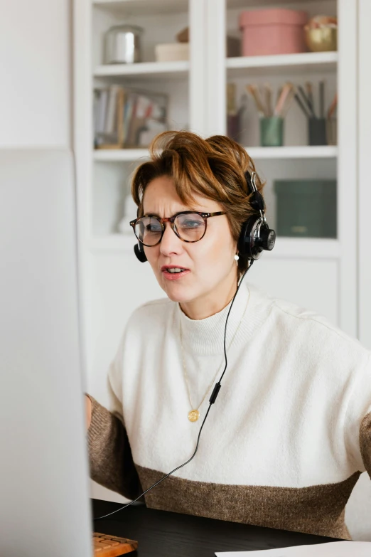 a woman sitting in front of a computer wearing headphones, wearing black rimmed glasses, talking, it specialist, thumbnail