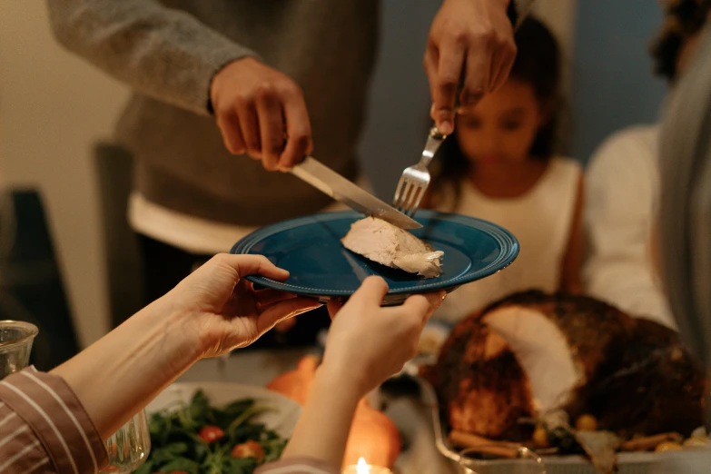 a person cutting a piece of meat on a blue plate, pexels contest winner, hurufiyya, victorian thanksgiving feast, avatar image, christmas night, family photo