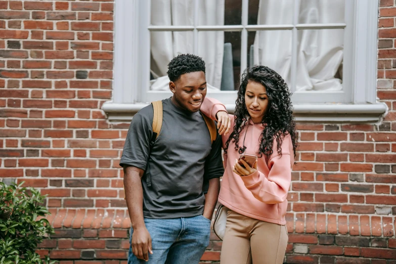 a man and woman standing in front of a brick building, trending on pexels, happening, black teenage boy, mobile learning app prototype, woman holding another woman, casually dressed