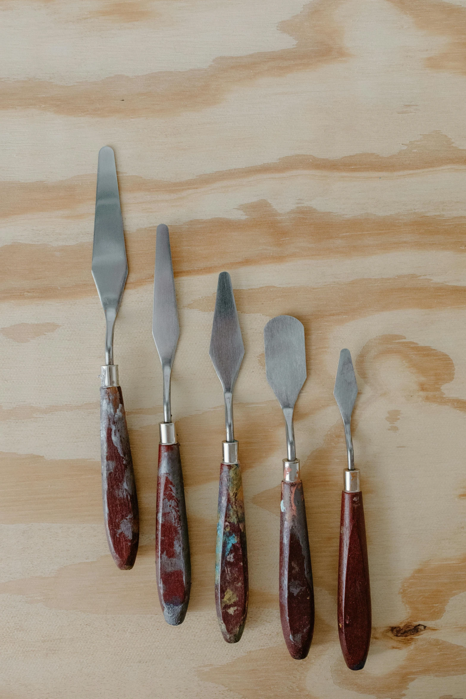 a group of knives sitting on top of a wooden table, a portrait, by Ann Thetis Blacker, teal silver red, spatula, marbled, detailed product image