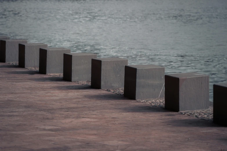 a row of concrete blocks sitting next to a body of water, unsplash, square lines, barriers, ((monolith)), metal scapes