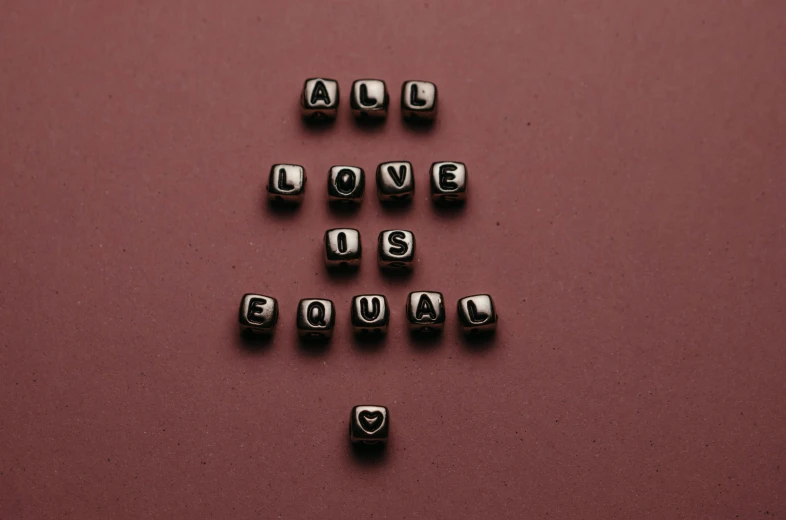 the word love is equal spelled in cubes on a pink surface, a black and white photo, by Julia Pishtar, pexels, minimalism, beads, gay, brown, this is it