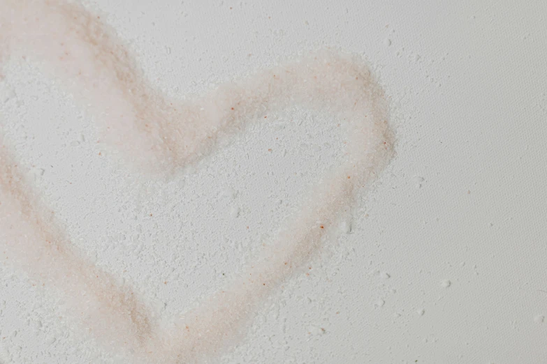 a close up of a heart drawn on a wall, by Emma Andijewska, trending on pexels, covered in salt, skincare, vanilla, on a white table